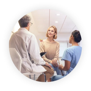 Photo image of an adult female patient speaking with doctor and nurse in a hospital setting, with an engineered mechanical yellow and magenta butterfly on her shoulder